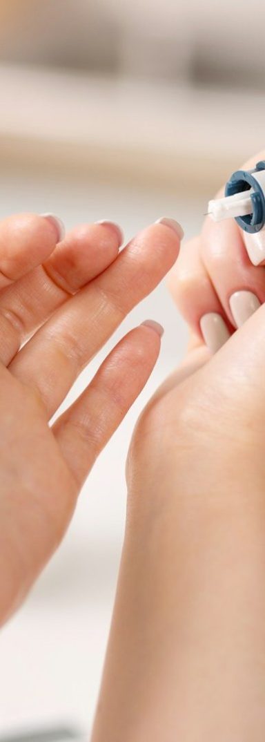 Hand, die im Begriff ist, sich eine Lanzette zur Blutabnahme in den Finger zu stechen.