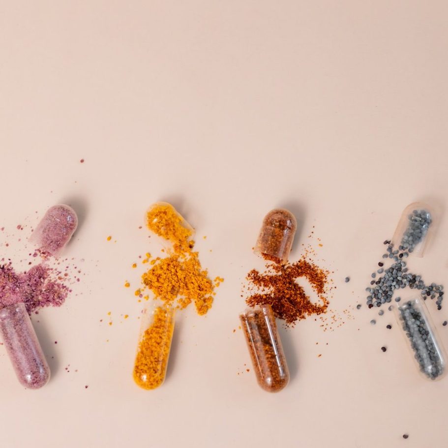 Kapseln Vier geöffnete Kapseln. Aus allen rieselt etwas Pulver heraus. Das Pulver hat jeweils verschiedene Farben.